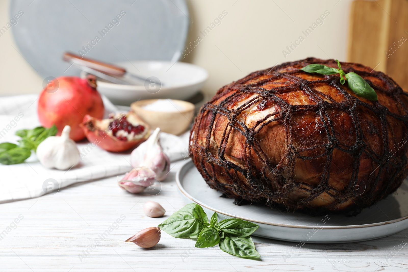 Photo of Delicious baked ham, basil leaves and garlic on white wooden table. Space for text