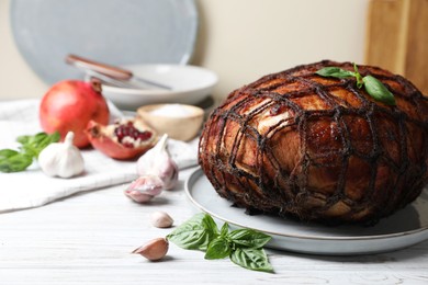 Delicious baked ham, basil leaves and garlic on white wooden table. Space for text