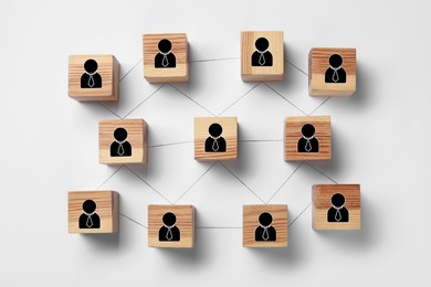 Teamwork. Wooden cubes with human icons linked together symbolizing cooperation on white background, top view