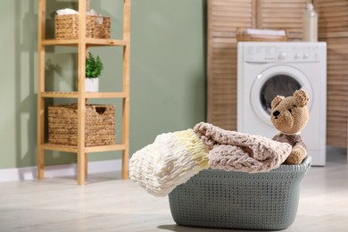 Photo of Laundry basket with soft blankets and toy in bathroom. Space for text
