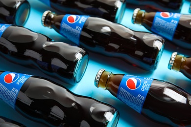 Photo of MYKOLAIV, UKRAINE - FEBRUARY 08, 2021: Glass bottles of Pepsi on light blue background, closeup