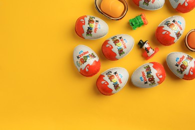 Photo of Sveti Vlas, Bulgaria - June 26, 2023: Kinder Surprise Eggs, plastic container and toys on orange background, flat lay. Space for text