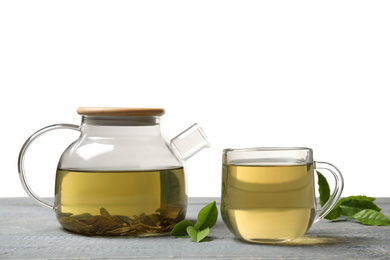 Cup of green tea, pot and leaves on grey wooden table