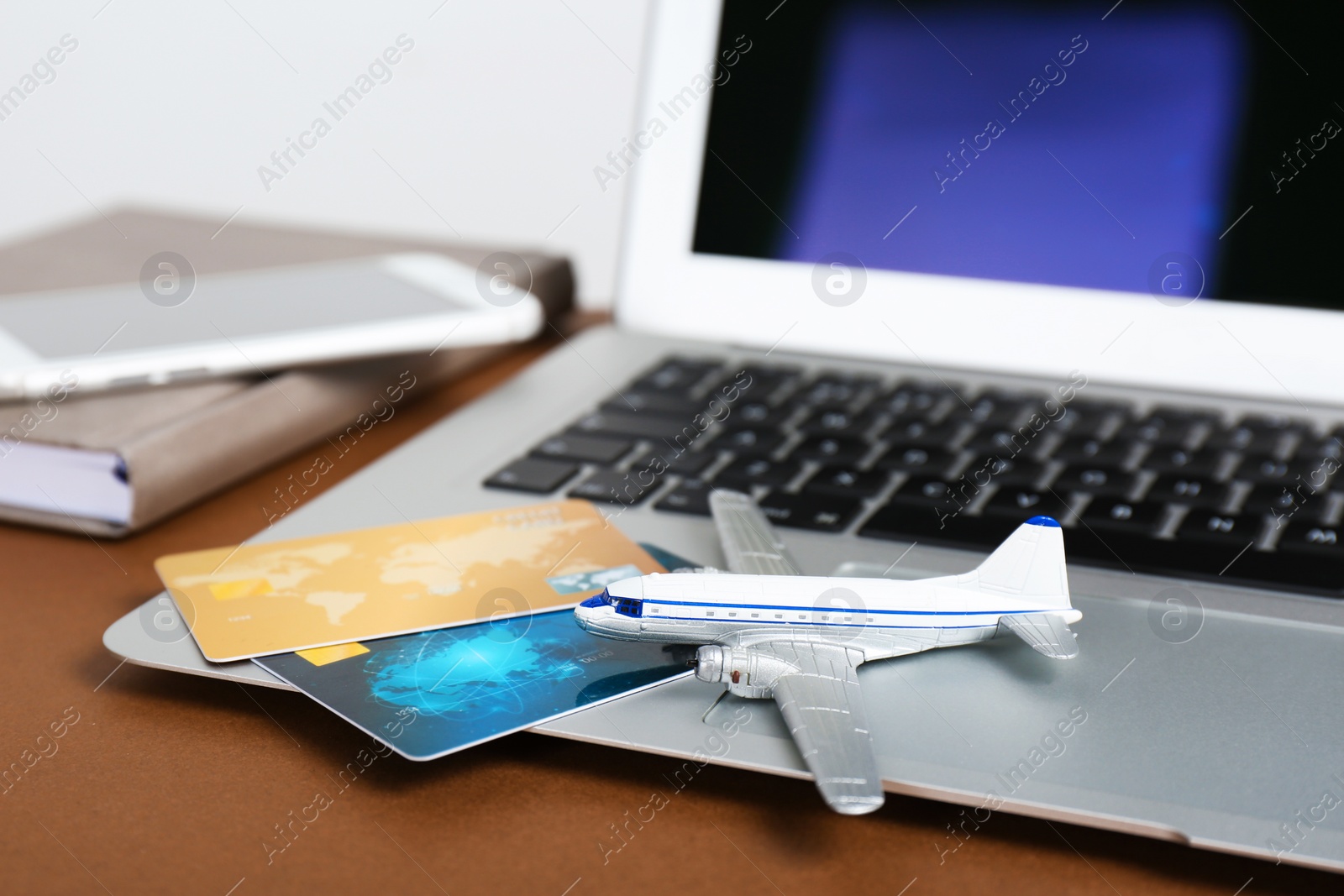 Photo of Composition with laptop, toy plane and credit cards on table. Travel agency