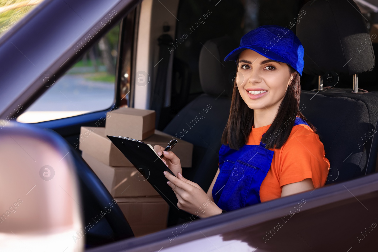 Photo of Courier with clipboard checking packages in car