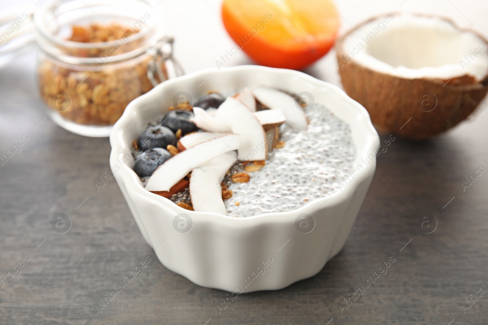 Photo of Bowl of tasty chia seed pudding with coconut, granola and blueberries on table