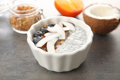 Bowl of tasty chia seed pudding with coconut, granola and blueberries on table