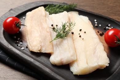 Raw cod fish, dill, tomatoes and spices on wooden table, closeup