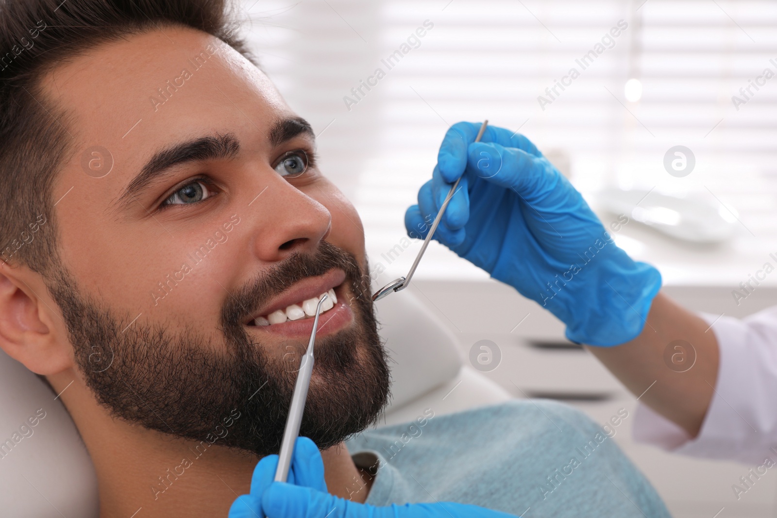 Photo of Dentist examining young man's teeth in clinic, closeup