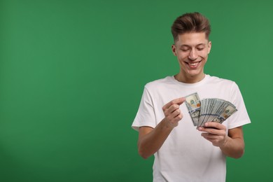 Photo of Happy man with dollar banknotes on green background. Space for text