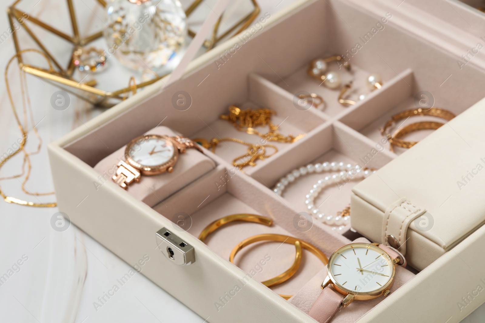 Photo of Jewelry box with many different accessories on white marble table, closeup