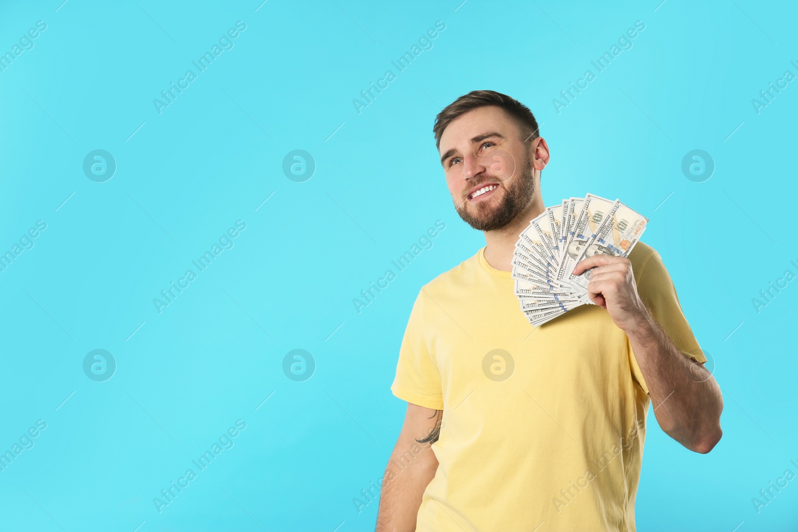 Photo of Portrait of happy young man with money on color background. Space for text