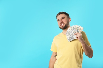 Photo of Portrait of happy young man with money on color background. Space for text