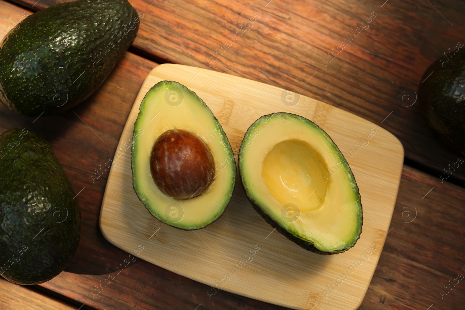 Photo of Tasty fresh avocados on wooden table, flat lay