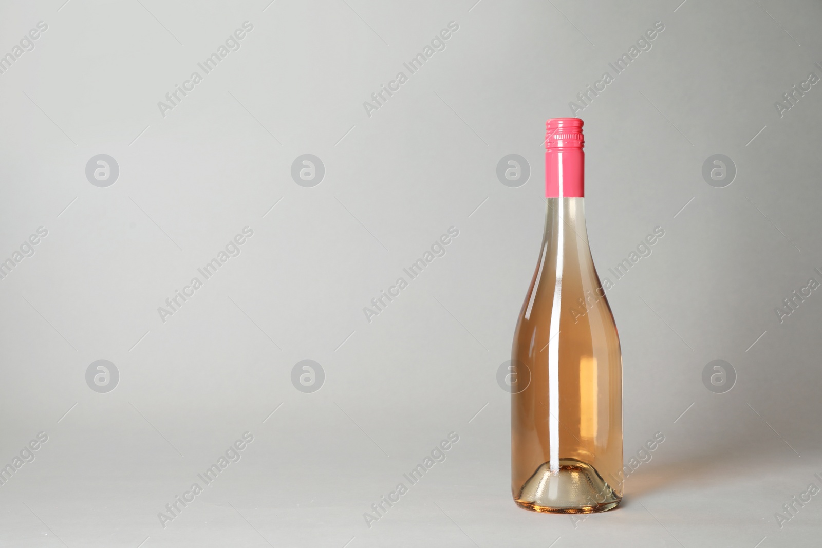 Photo of Bottle of wine on grey background. Space for text