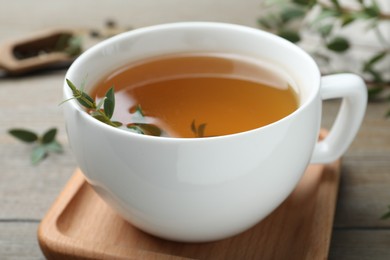 Photo of Cup of aromatic eucalyptus tea on wooden table, closeup