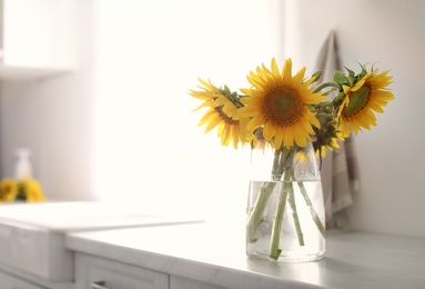 Photo of Vase with beautiful yellow sunflowers in kitchen, space for text