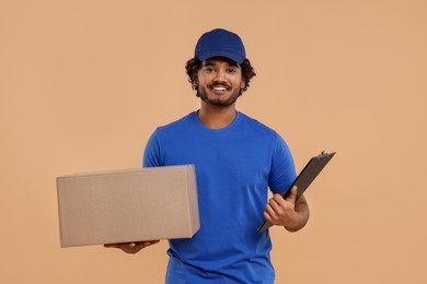 Photo of Happy courier with parcel and clipboard on light brown background