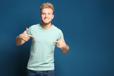 Photo of Young man wearing blank t-shirt on blue background. Mockup for design