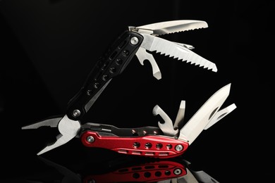 Photo of Compact portable colorful multitool on black background