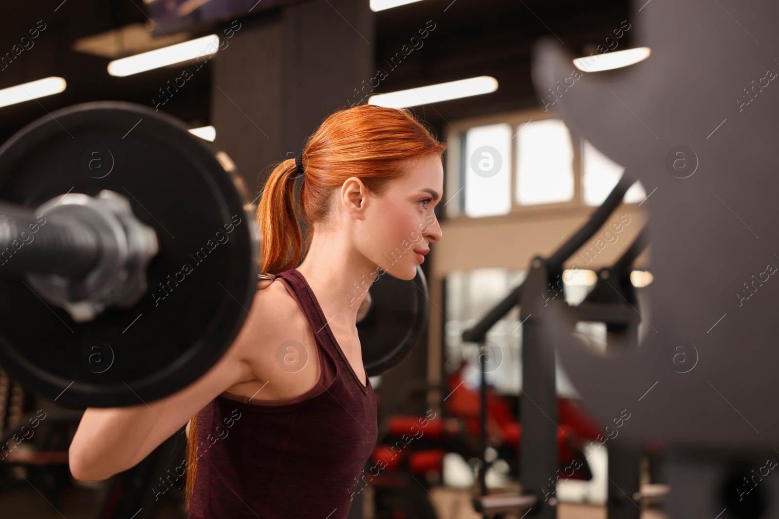 Photo of Athletic young woman with barbell training in gym