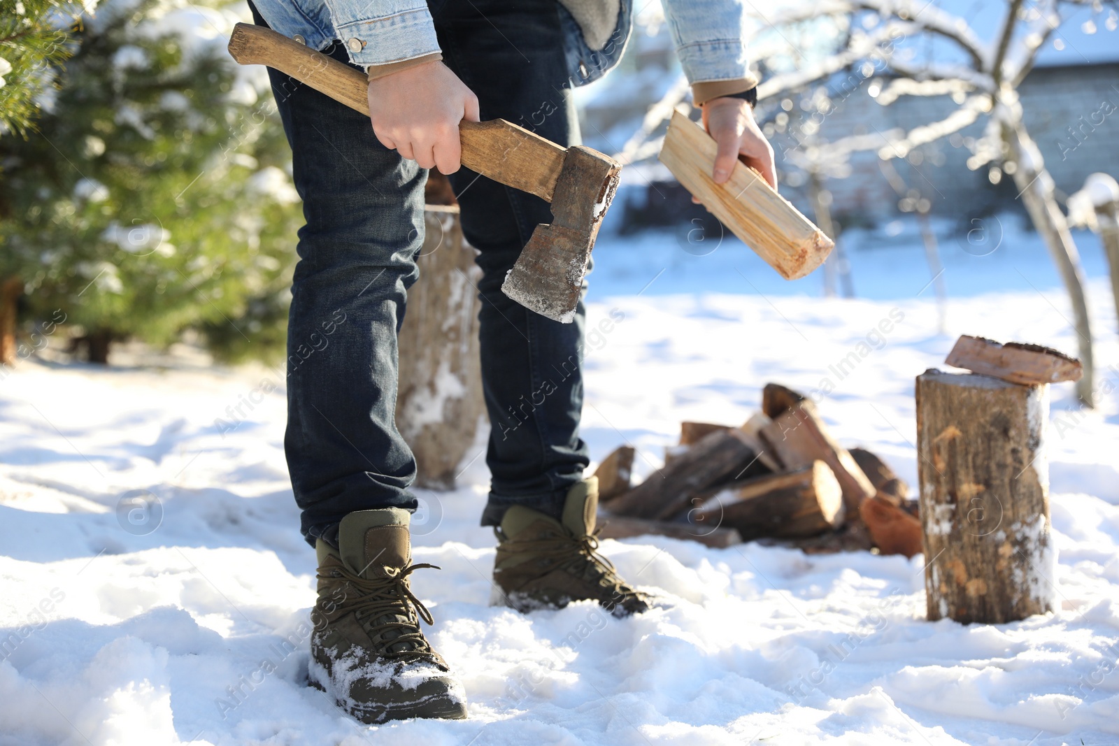 Photo of Man chopping wood with axe outdoors on winter day, closeup