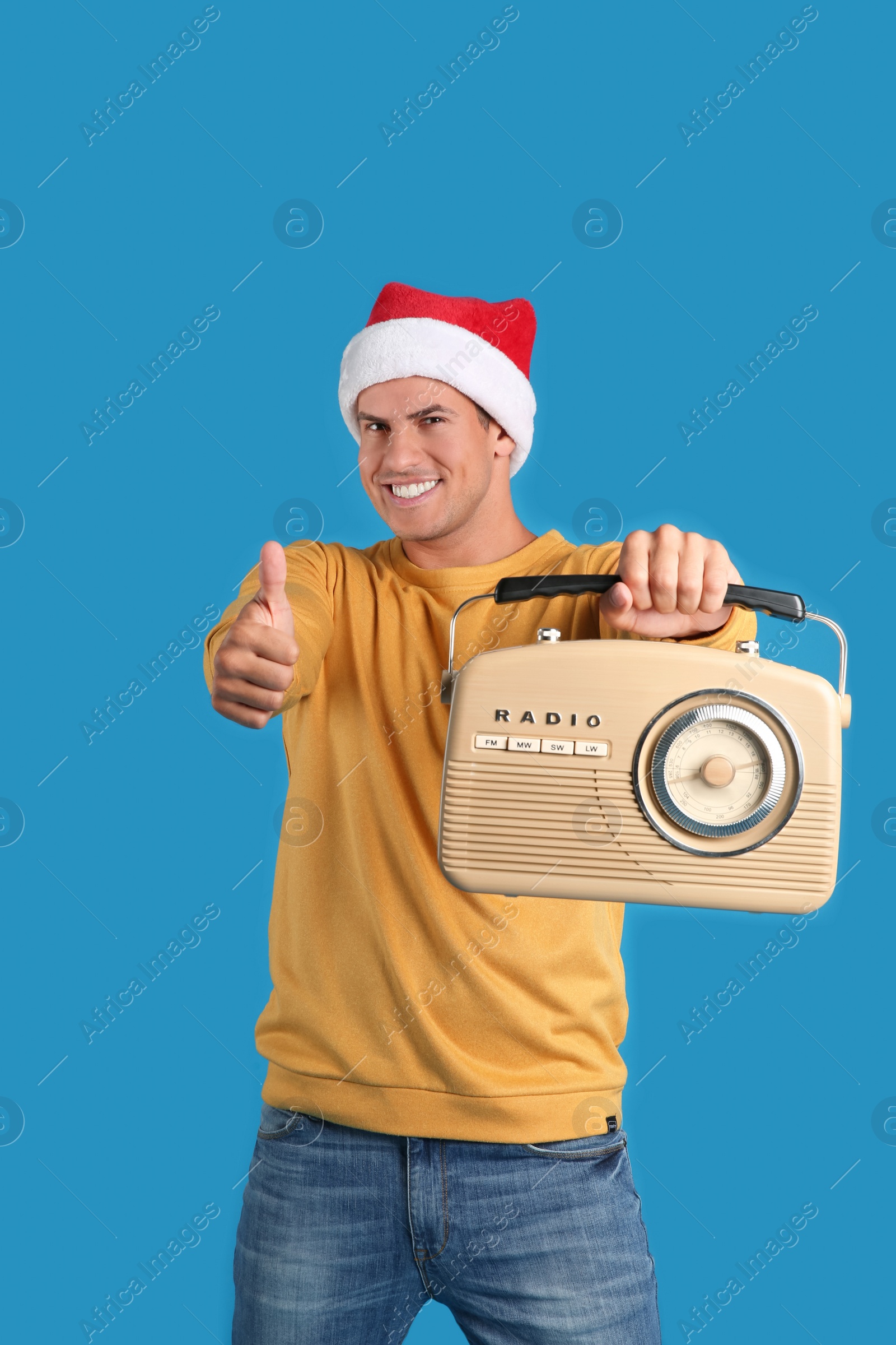 Photo of Happy man with vintage radio on blue background. Christmas music