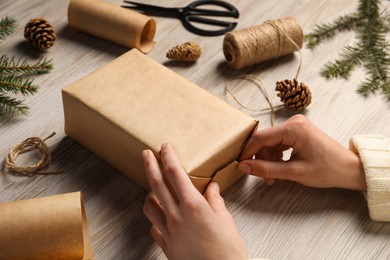 Photo of Woman decorating gift box at white wooden table, closeup. Christmas present