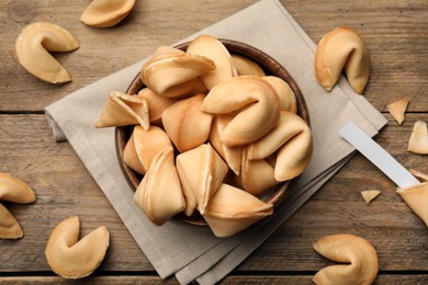 Tasty fortune cookies and paper with prediction on wooden table, flat lay