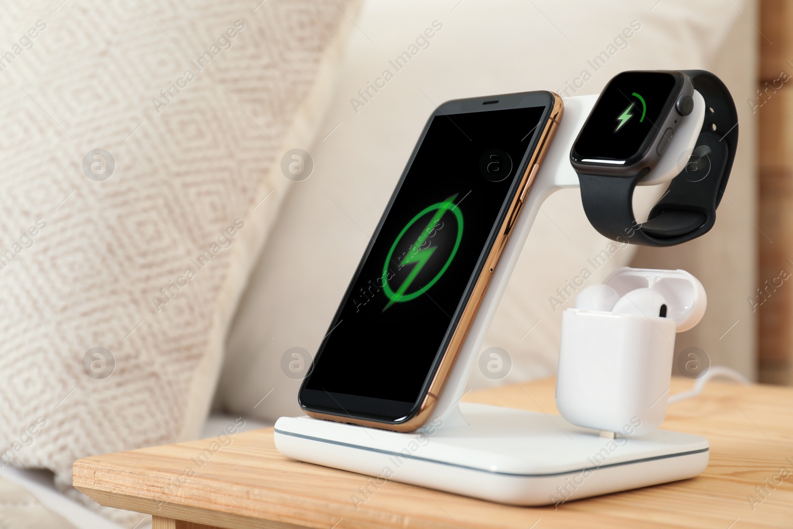 Photo of Different gadgets charging on wireless pad in bedroom, closeup
