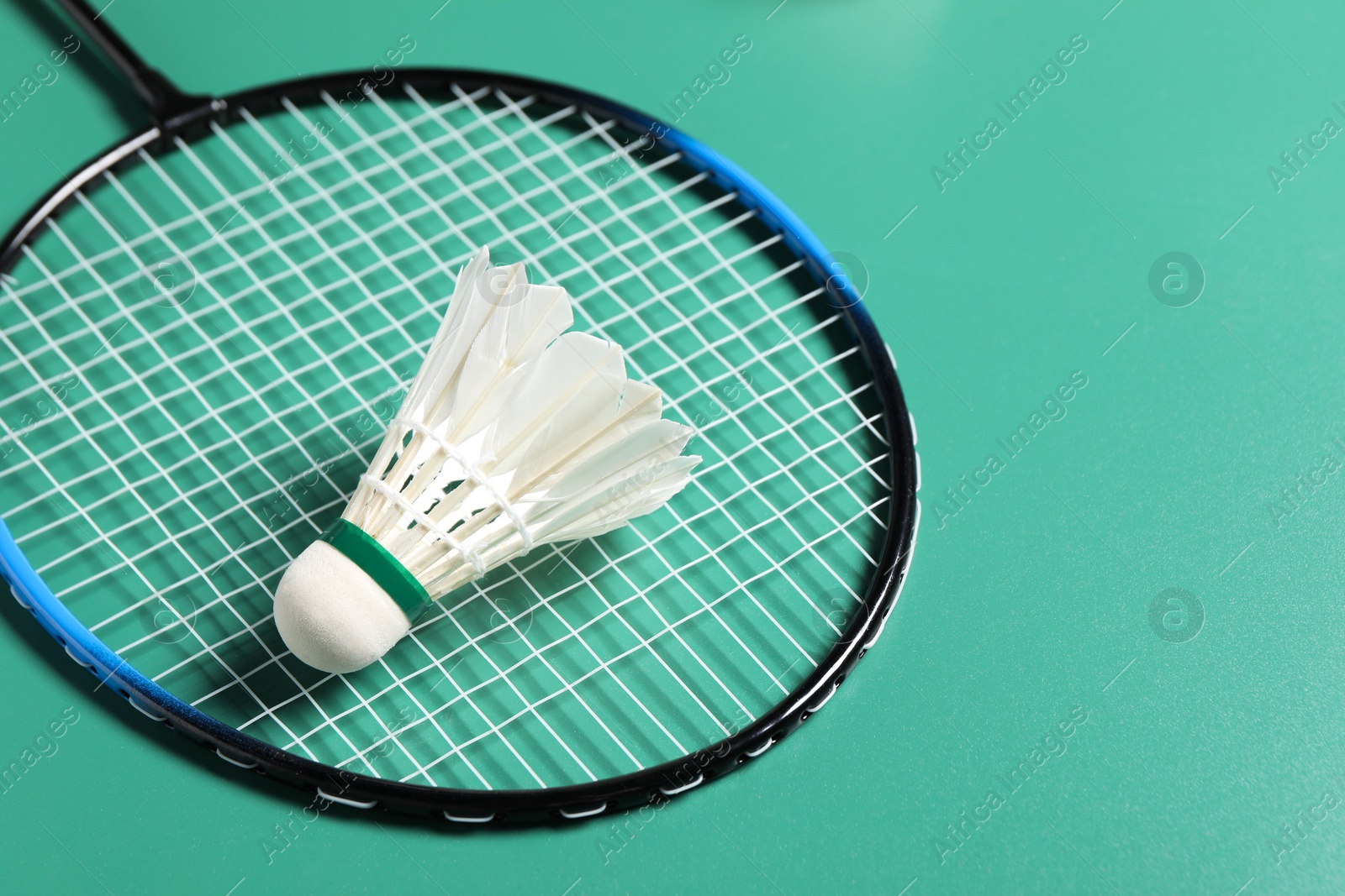 Photo of Feather badminton shuttlecock and racket on green background, closeup