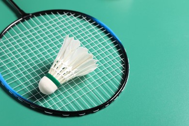 Feather badminton shuttlecock and racket on green background, closeup