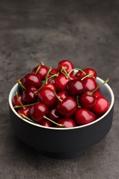 Photo of Bowl with ripe sweet cherries on dark grey table