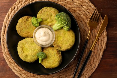 Tasty vegan cutlets served with sauce on wooden table, top view