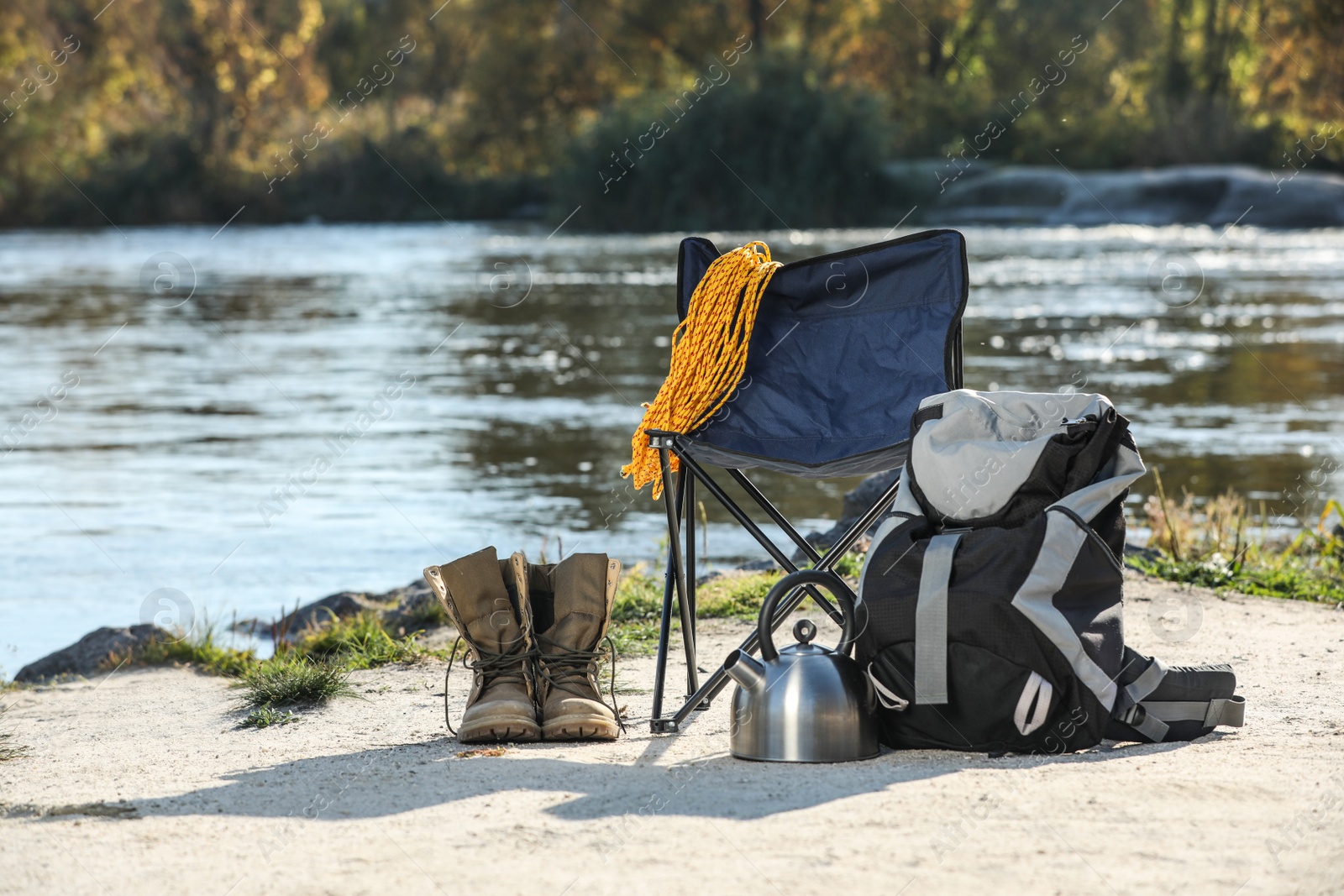 Photo of Set of camping equipment on sand near pond