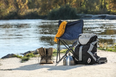 Photo of Set of camping equipment on sand near pond