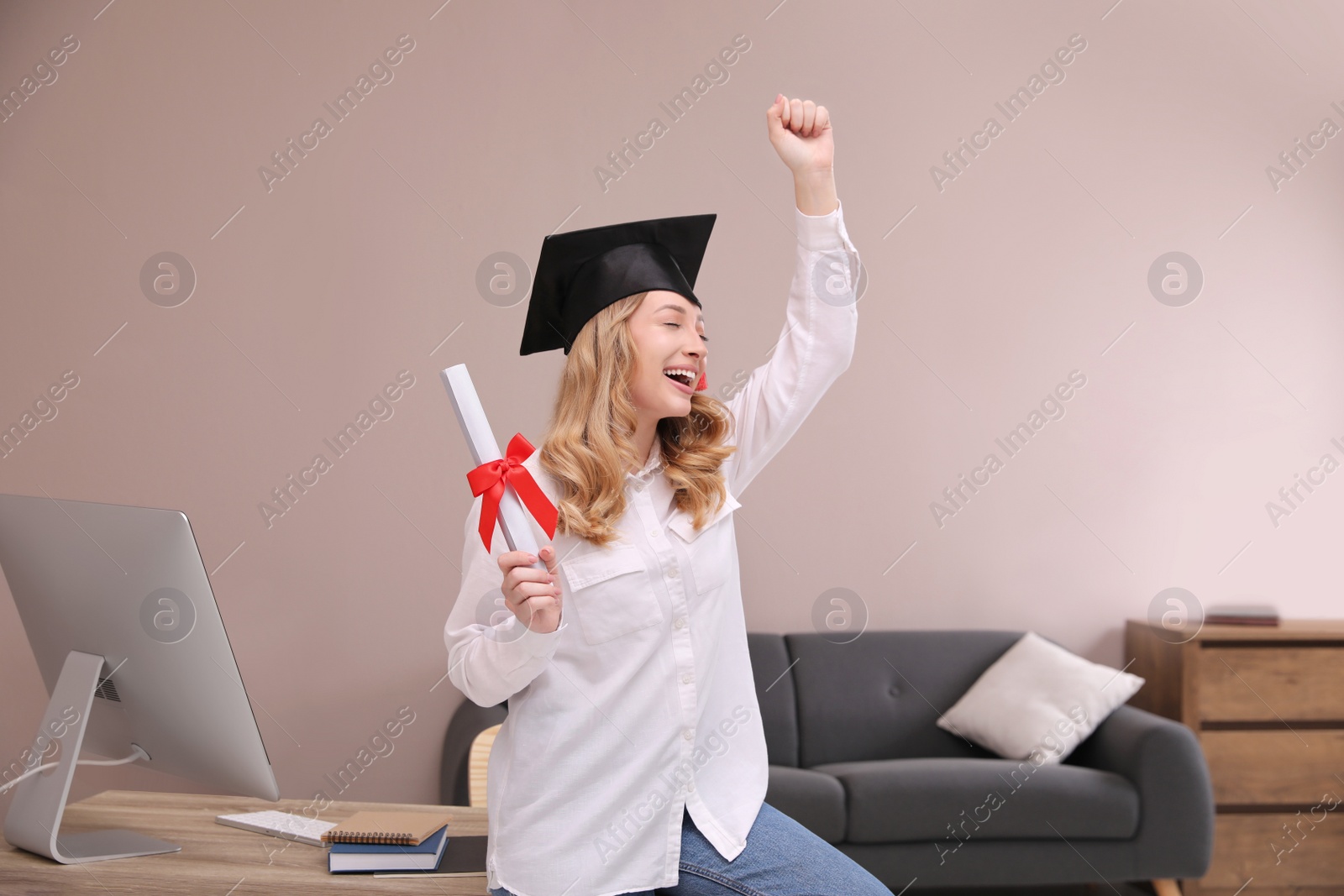 Photo of Emotional student with graduation hat and diploma at workplace in office