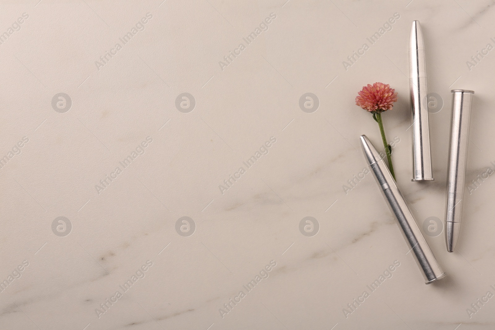 Photo of Bullets and beautiful flower on light marble table, flat lay. Space for text