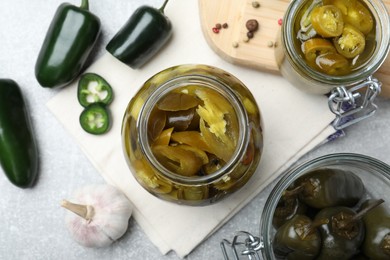 Flat lay composition with pickled green jalapeno peppers on light grey table