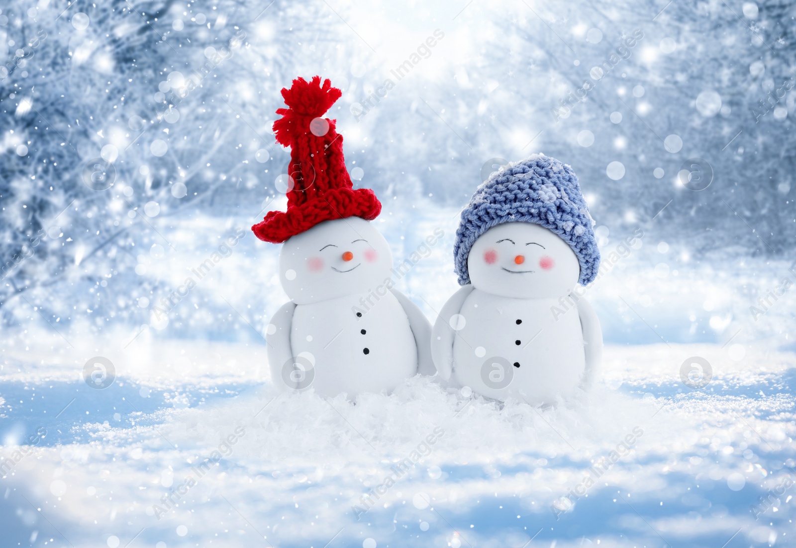 Image of Cute decorative snowmen in hats outdoors on snowy day