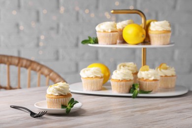 Photo of Delicious lemon cupcakes with white cream served on wooden table