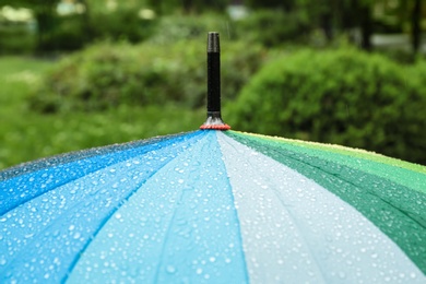 Photo of Bright modern umbrella under rain in green park, closeup