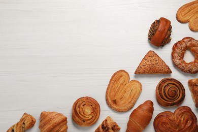 Different tasty freshly baked pastries on white wooden table, flat lay. Space for text