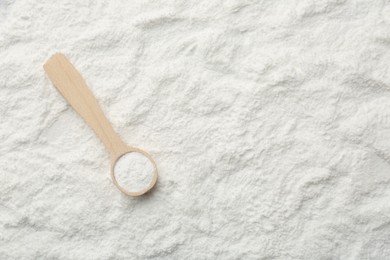 Photo of One wooden spoon on baking powder, top view. Space for text