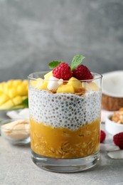 Delicious chia pudding with mango, raspberries and granola on light grey table