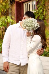 Photo of Bride and groom kissing behind bouquet of flowers on wedding day