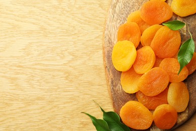Tasty apricots and green leaves on wooden table, top view with space for text. Dried fruits