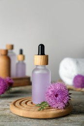 Photo of Bottle of essential oil and flower on wooden table