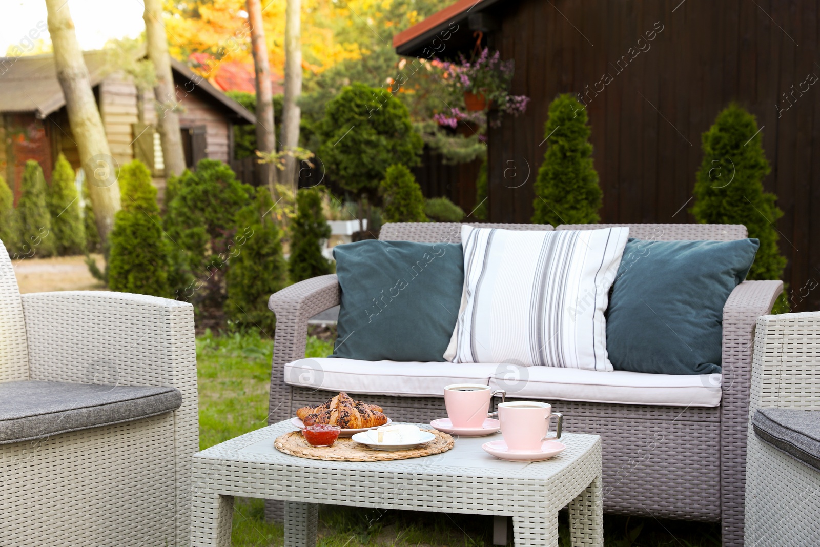 Outdoor breakfast with tea and croissants on rattan table in garden Photo of Outdoor breakfast with tea and croissants on rattan table in garden