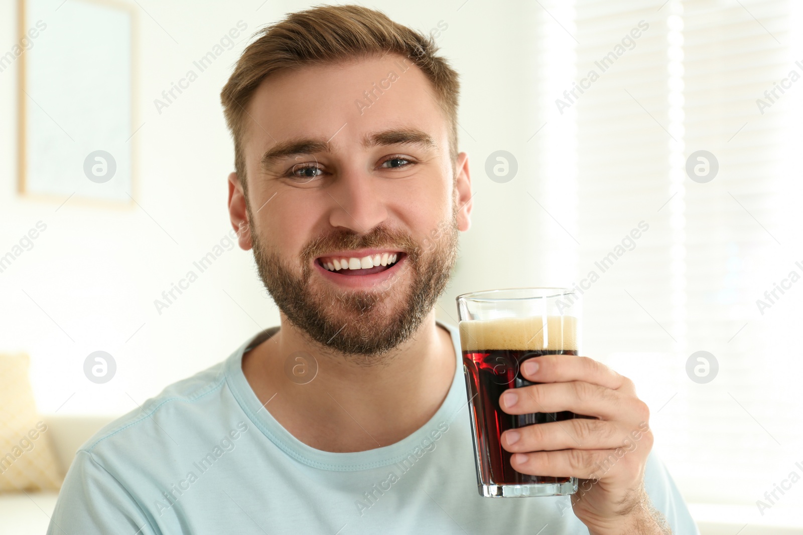 Photo of Handsome man with cold kvass indoors. Traditional Russian summer drink